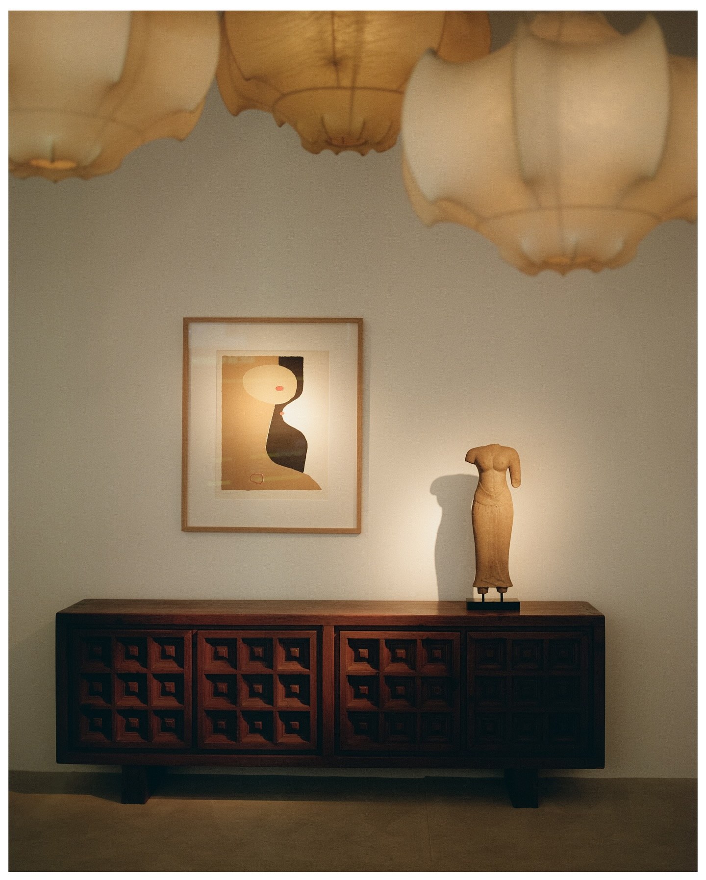 Lit sideboard, framed print and silk pendant lamps in a hotel room